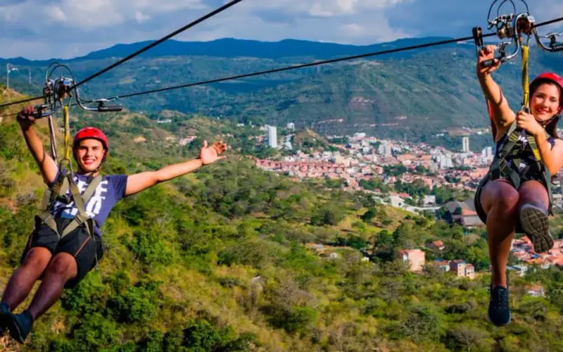 Dos personas colgadas del cable vuelo sobre las montañas