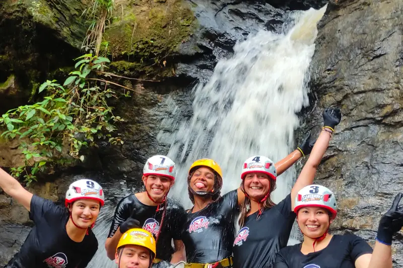 Grupo con casco y arnés frente a una cascada