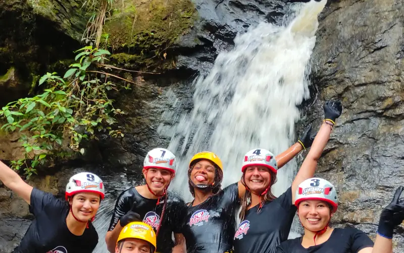 Grupo con casco y arnés frente a una cascada