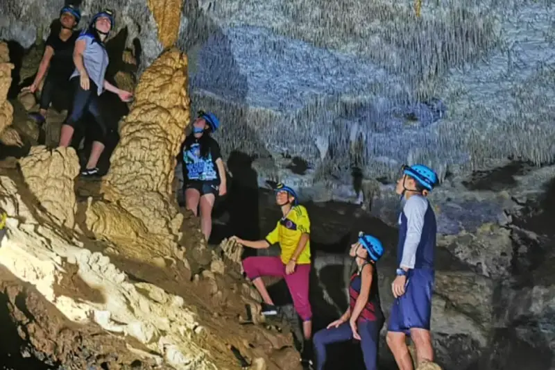 Grupo con cascos entre estalactitas en la Cueva de la Vaca