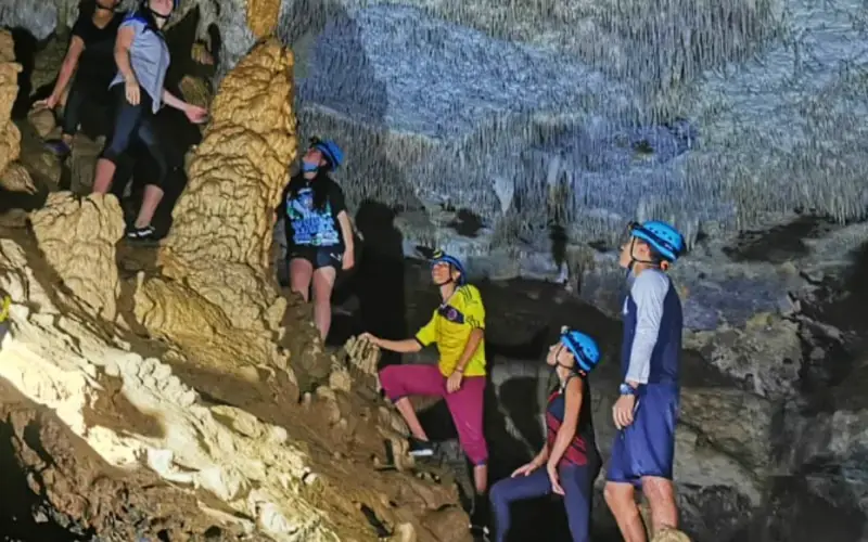 Grupo con cascos entre estalactitas en la Cueva de la Vaca