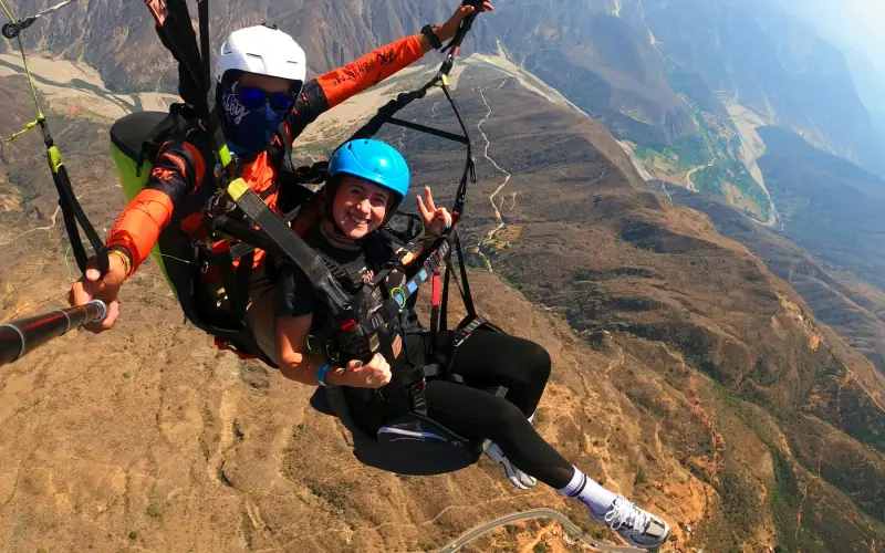 Pasajero y piloto en parapente con el cañón del Chicamocha abajo