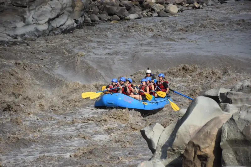 Balsa de rafting con remeros de casco azul en las olas cafés del río Suárez